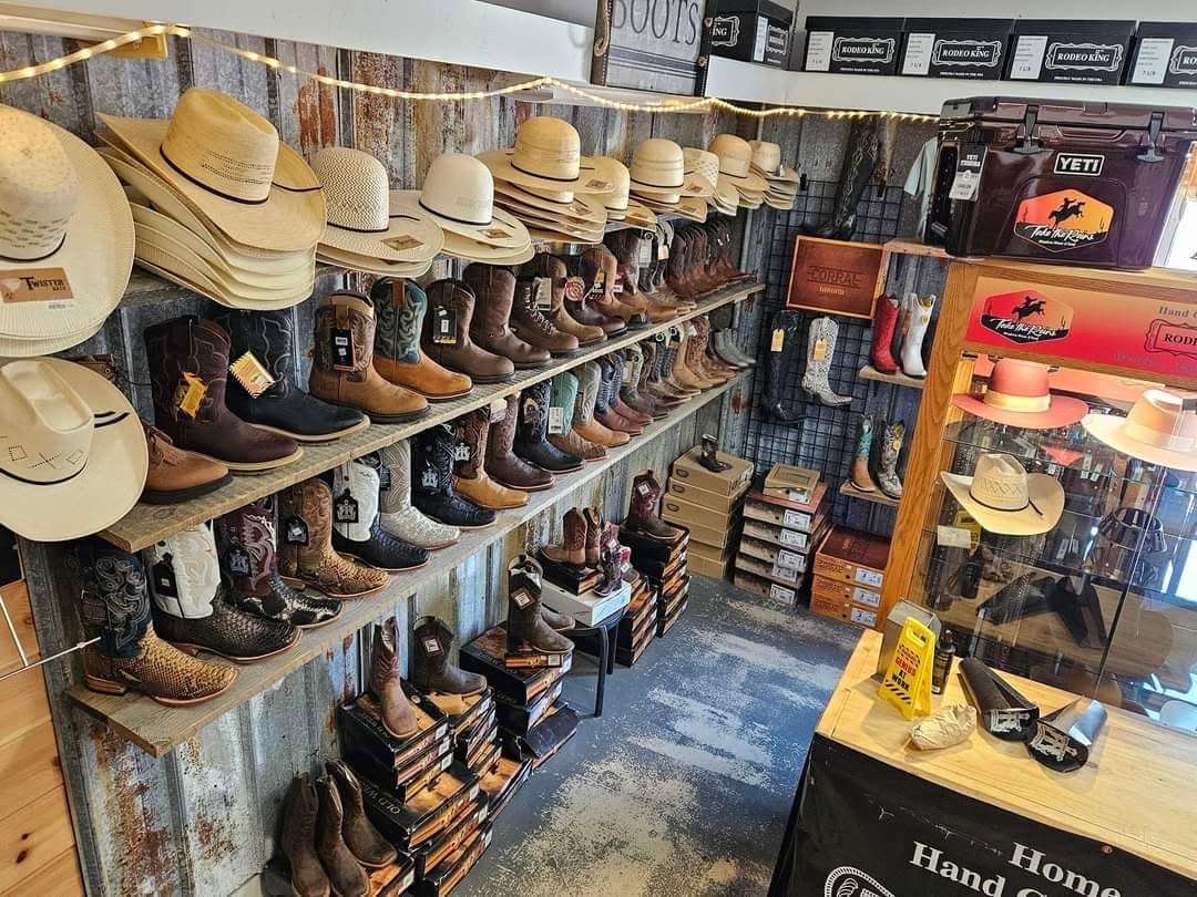 A wall of cowboy boots and western goods inside Take the Reins